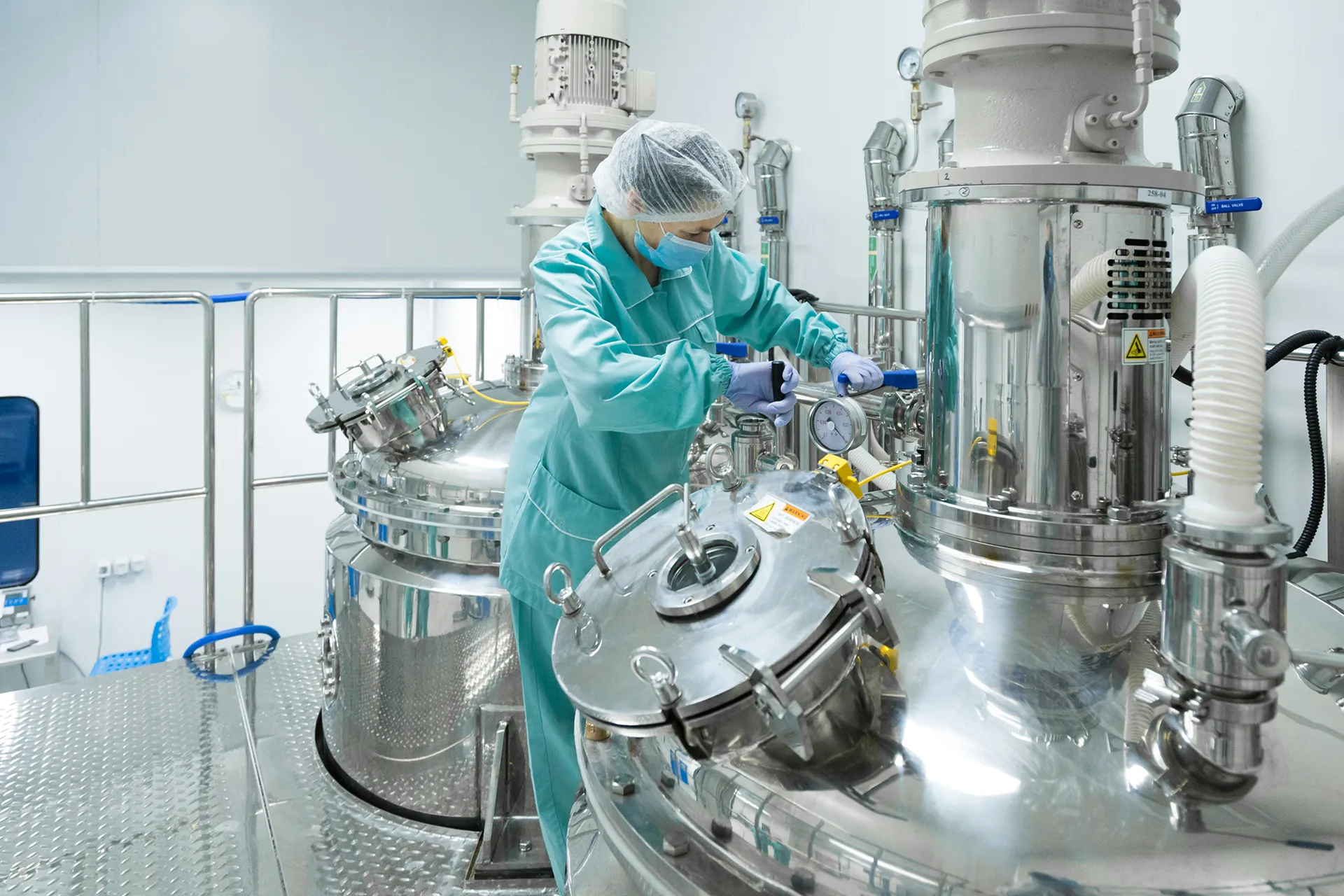 Fully hooded person working on equipment in a clean room